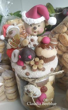 there are many cookies and cupcakes in the glass jar with santa hats on top