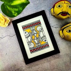 two yellow masks sitting next to each other on top of a cement floor with flowers