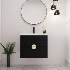 a black and white bathroom with a round mirror on the wall next to a plant