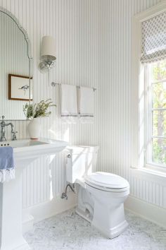 a white toilet sitting next to a sink in a bathroom