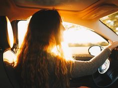 a woman sitting in the back seat of a car with her long hair hanging out