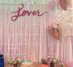 a table topped with lots of cake and balloons next to a wall covered in pink sequins