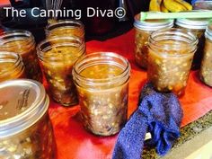 several jars filled with food sitting on top of a red table cloth next to bananas