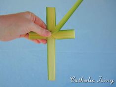 a hand holding a piece of yellow paper in the shape of a cross on a blue background