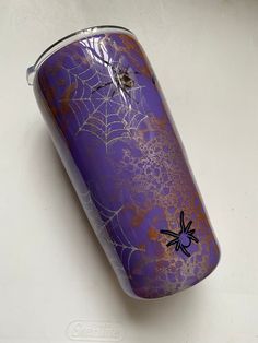 a purple can with spider webs on it sitting on top of a white table