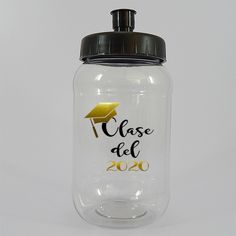 a clear glass jar with a black lid and a gold graduation cap on the top