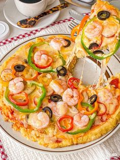 a pizza with shrimp, peppers and olives is being served on a platter