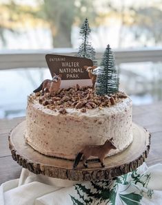 a cake with frosting and trees on top is sitting on a wooden platter