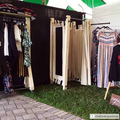 clothes are hanging on racks in front of a tent