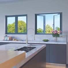 a modern kitchen with marble counter tops and stainless steel appliances in front of large windows