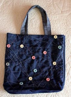 a blue bag with buttons on it sitting on top of a white bed next to a wall