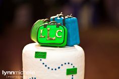 a close up of a white cake with green and blue bags on it's top