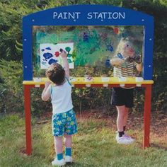 two children standing in front of a painting station