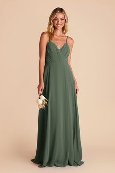 a woman in a long green bridesmaid dress holding a bouquet and smiling at the camera