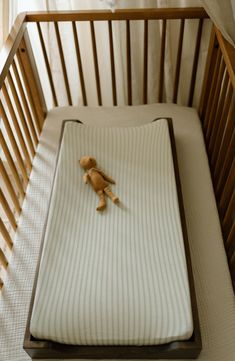 a teddy bear laying on top of a baby crib