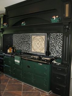 a kitchen with green cabinets and black counter tops, tile backsplashing on the wall