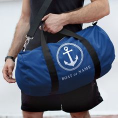 a man carrying a blue duffle bag with an anchor on the front and name