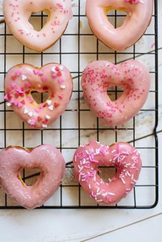 six doughnuts with pink and white sprinkles arranged on a cooling rack