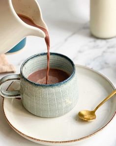 a person pouring chocolate into a cup on a plate