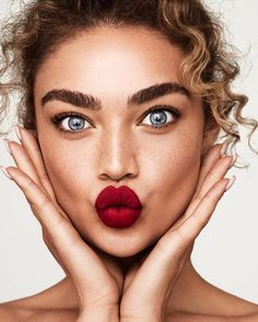 a woman with red lipstick and freckles on her face posing for the camera