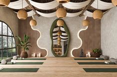 a large room with yoga mats and bamboo lights hanging from the ceiling, along with potted plants