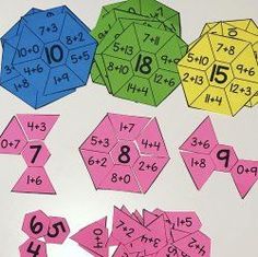 colorful numbers and shapes are arranged on a white surface with pink, blue, green, yellow, and purple paper