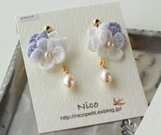 a pair of white and blue flower earrings with pearls on them sitting on top of a card