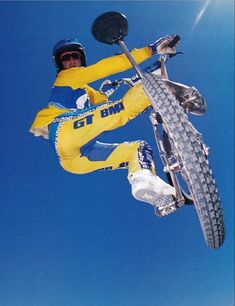 a man flying through the air while riding a motorcycle on a dirt bike course in front of a blue sky