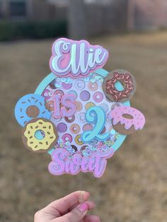 a person holding up a sticker with donuts on it that says, ellie is sweet