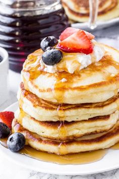 a stack of pancakes with syrup and fruit on top