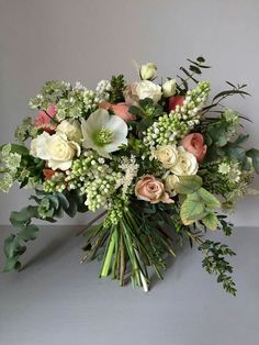 a bouquet of flowers sitting on top of a white table next to a gray wall