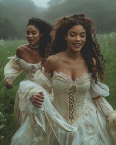 two women in white dresses are walking through the grass