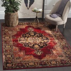 a red rug with an ornate design on it in front of a chair and potted plant