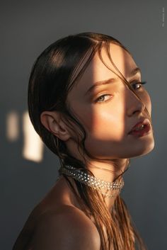 a woman with long hair and pearls on her neck is looking off to the side