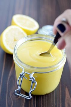 a person is using a knife to cut lemons into small jars on a table