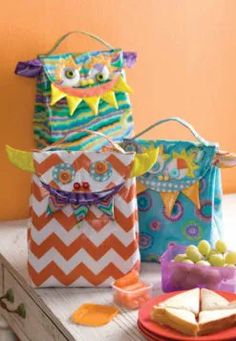 three colorful bags sitting on top of a table next to some cookies and candy bars