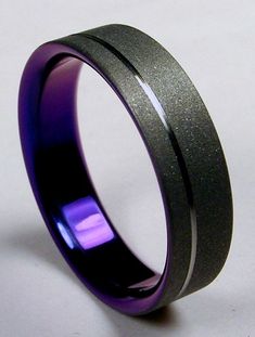 a purple and black wedding ring with an inlay on the inside is shown against a white background