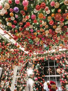 christmas decorations hanging from the ceiling in a room filled with trees and other holiday items