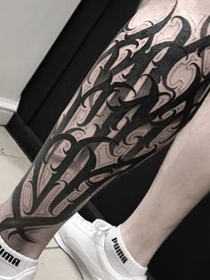 a man's leg with a black and white tattoo design on the calf area