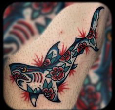 a shark tattoo on the arm with roses and leaves around it's neck,