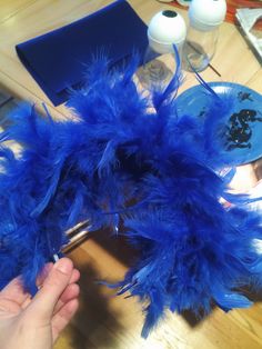 a person is holding some blue feathers on a table