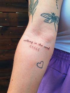 a woman's arm with a dragonfly on it and the words walking in the wind