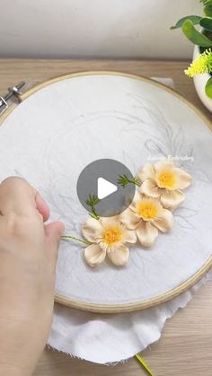 a person is working on some flowers in a hoop