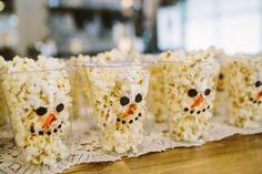 snowman popcorn cups are lined up on a table