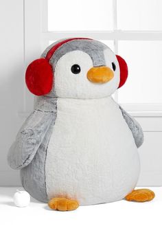 a stuffed penguin with headphones on sitting in front of a white wall and window