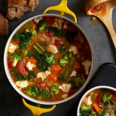 two bowls of soup with broccoli, cauliflower and carrots next to bread