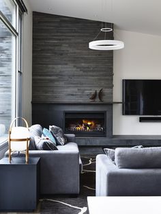 a living room with two couches and a television mounted on the wall next to a fire place