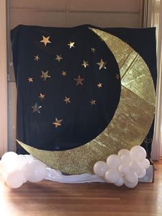 a large black and gold moon with stars on it, surrounded by balloons in front of a doorway