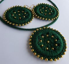 two pieces of green and gold beaded jewelry on a white surface with beads around it