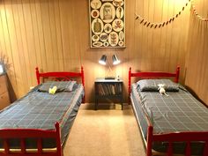 two twin beds in a room with wood paneling and string lights on the wall